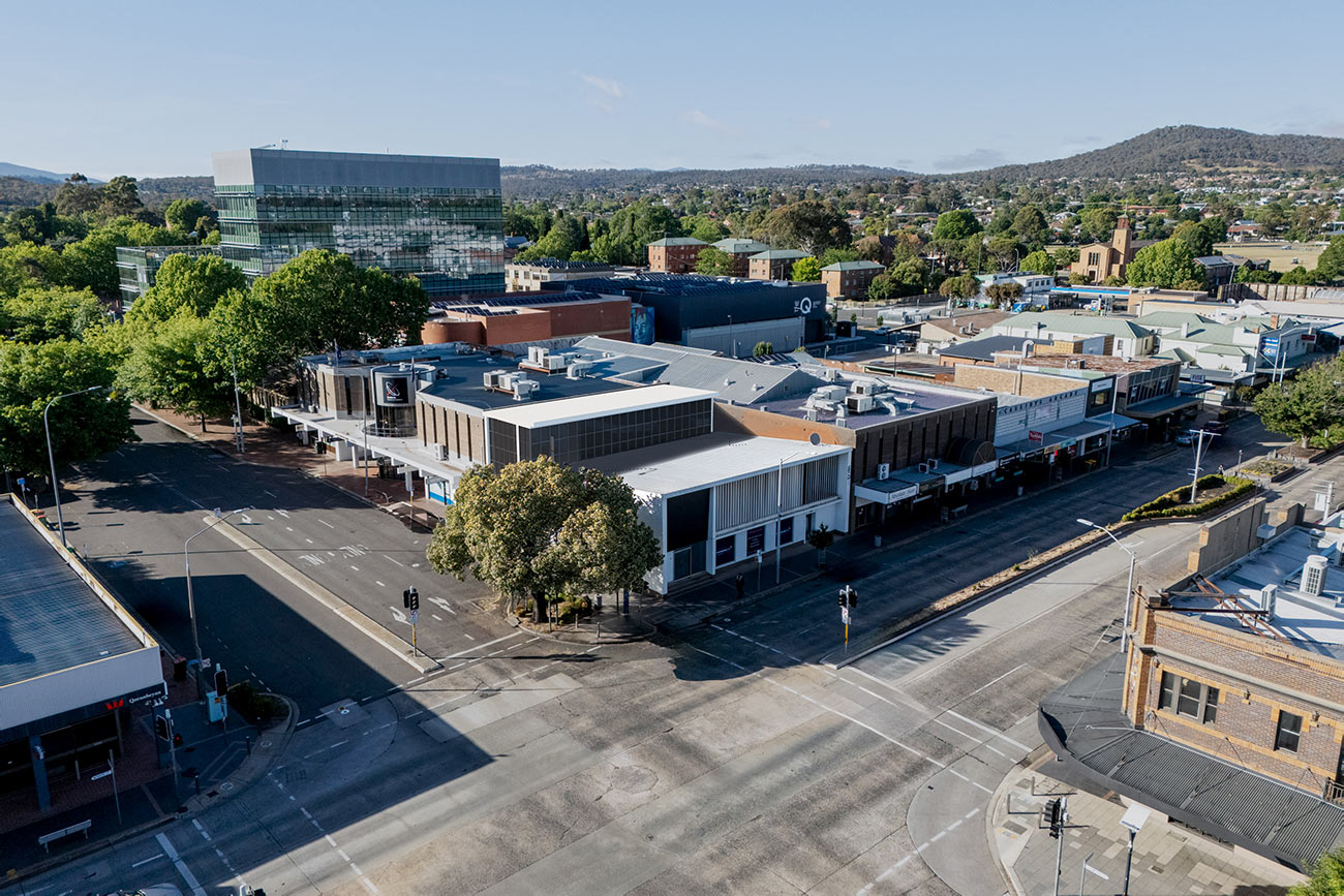 3D Render aerial view of commercial buildings in an urban district with streets trees and surrounding cityscape in daylight