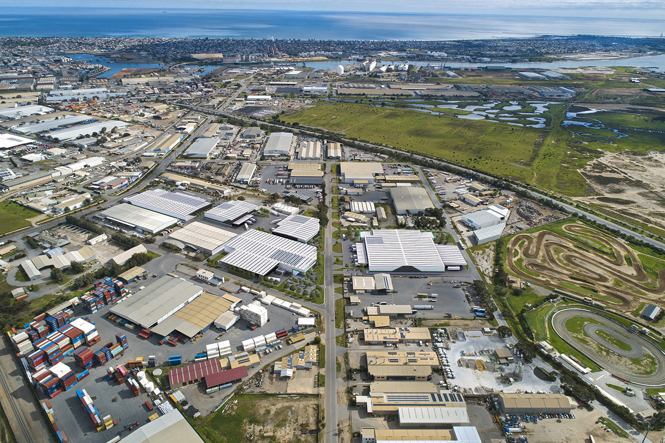 3D Render photomontage aerial view of industrial precinct with warehouses logistics facilities shipping containers road networks and coastal landscape