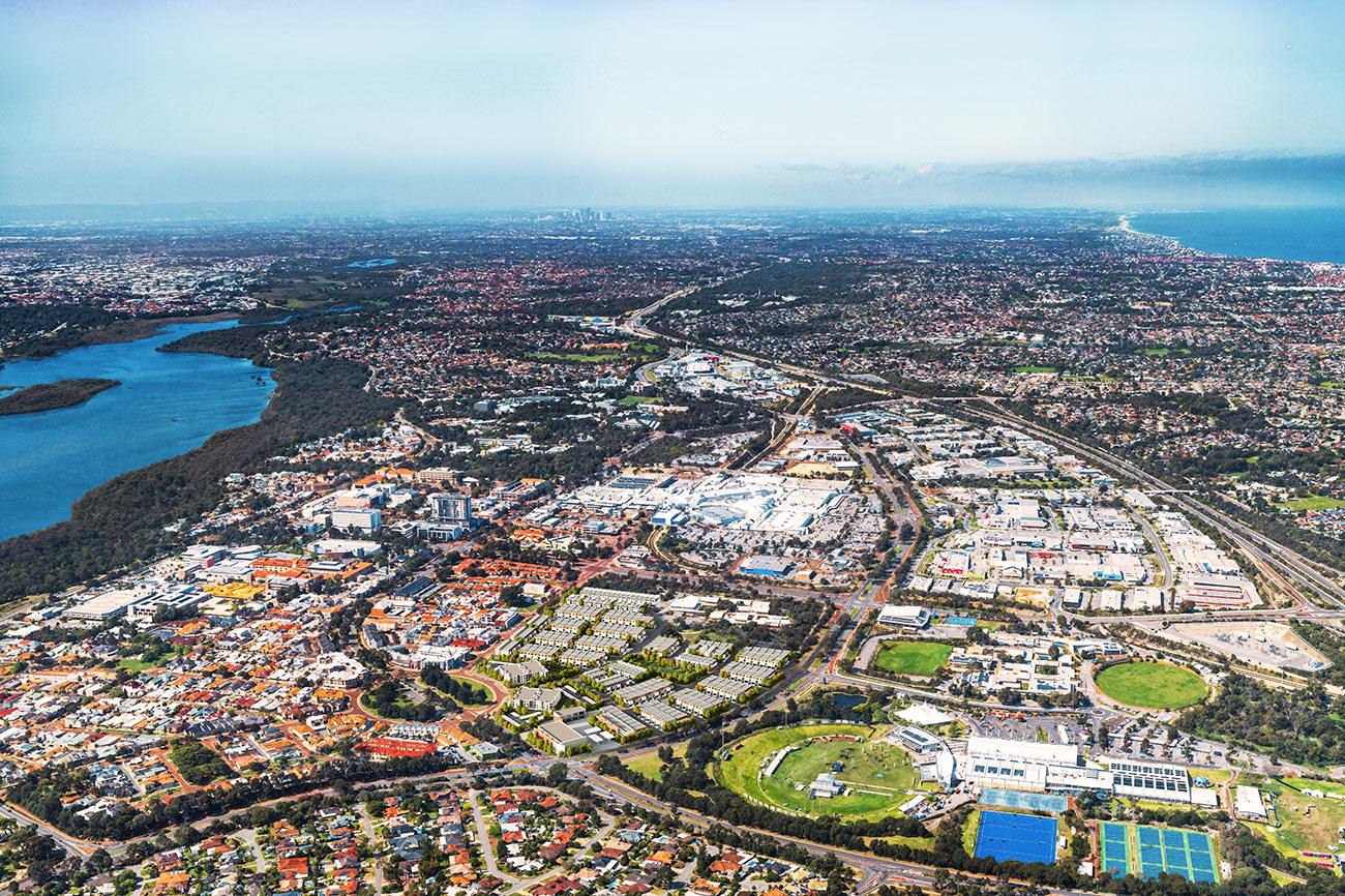 3D Render photomontage aerial view of suburban residential masterplan with housing development roads green spaces commercial areas and coastal city surroundings